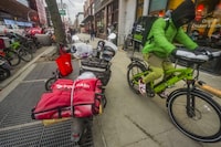 A food delivery worker rides off after a pickup from a fast-food restaurant on Brooklyn's Flatbush Avenue, Monday, Jan. 29, 2024, in New York. A wage law in New York City meant to protect food delivery workers is getting backlash from app companies like Uber, GrubHub and DoorDash, who have cut worker hours and made it more difficult to tip. (AP Photo/Bebeto Matthews)