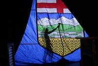 A campaign worker steams the wrinkles from a large Alberta flag at an event venue in Calgary, Alta., Tuesday, April 16, 2019. The posting for a new high-level Alberta government job supposed to help the province align with environmental concerns from financial markets seems more about talk than action, observers say. THE CANADIAN PRESS/Jeff McIntosh