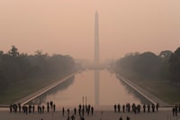 With the Washington Monument in the background and a thick layer of smoke, Marine Corps honor color guard rehearse, Thursday, June 8, 2023, in Washington. Intense Canadian wildfires are blanketing the northeastern U.S. in a dystopian haze, turning the air acrid, the sky yellowish gray and prompting warnings for vulnerable populations to stay inside. (AP Photo/Jose Luis Magana)