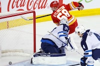 Winnipeg Jets goalie Connor Hellebuyck is scored on by Calgary Flames' Oliver Kylington (58) during first period NHL hockey action in Calgary, Alta., Monday, Feb. 19, 2024. THE CANADIAN PRESS/Larry MacDougal