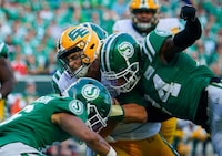 Edmonton Elks quarterback Taylor Cornelius (15) is tackled by Saskatchewan Roughriders defensive back Deontai Williams (24) and defensive back Amari Henderson (16) during the first half of CFL football action in Regina, on Thursday, July 6, 2023. THE CANADIAN PRESS/Heywood Yu