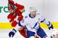 Tampa Bay Lightning centre Steven Stamkos (91) tries to defend against Calgary Flames centre Dillon Dube (29) after losing his stick during first period NHL hockey action in Calgary on Saturday Dec. 16, 2023. THE CANADIAN PRESS/Larry MacDougal