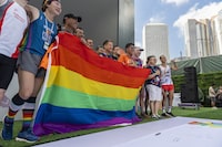 Participants hold the rainbow flag at the AIDS Quilt Memorial Ceremony, ahead of the Gay Games in Hong Kong, Saturday, Nov. 4, 2023. The first Gay Games in Asia are fostering hopes for wider LGBTQ+ inclusion in the regional financial hub, following recent court wins in favor of equality for same-sex couples and transgender people. (AP Photo/Chan Long Hei)