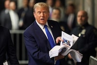 Former US president Donald Trump holds press clippings as he speaks to the press at the conclusion of the third day of his trial for allegedly covering up hush money payments linked to extramarital affairs at Manhattan Criminal Court in New York on April 18, 2024. A panel of 12 jurors was sworn in on Thursday to sit in judgement of Donald Trump at the unprecedented criminal trial of a former US president. (Photo by Brendan McDermid / POOL / AFP) (Photo by BRENDAN MCDERMID/POOL/AFP via Getty Images)