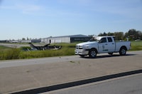 A Langley Township pickup truck is seen damaged after being hit by a plane, left, which crashed at the airport in Langley, B.C., Tuesday, May 2, 2023. Langley Township deputy fire chief Russ Jenkins said the crash happened at about 3:30 p.m. on Tuesday, when the plane came down over the road next to the airport. THE CANADIAN PRESS/Curtis Kreklau