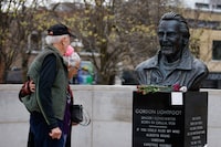 People look at a statue of Gordon Lightfoot adorned with flowers, after the prolific Canadian singer-songwriter died in a Toronto hospital at the age of 84, in his birthplace in Orillia, Ontario, Canada May 2, 2023.  REUTERS/Cole Burston