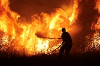 A firefighter tries to extinguish a wildfire burning at the industrial zone of the city of Volos, in central Greece, July 26, 2023. REUTERS/Alexandros Avramidis     TPX IMAGES OF THE DAY