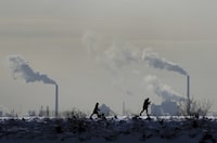 People cross-country ski in the cold weather as an industrial plant is shown in the back ground in Toronto on Friday, Feb. 4, 2022. Environment Minister Steven Guilbeault says Canada is issuing a challenge to the rest of the world to expand the use of carbon pricing in the fight against greenhouse gas emissions. THE CANADIAN PRESS/Nathan Denette