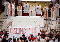 Indigenous people hold a banner that reads ""Rescind the Doctrine"" as Pope Francis presides over a mass at the Shrine of Sainte-Anne-de-Beaupre, in Quebec on July 28, 2022.