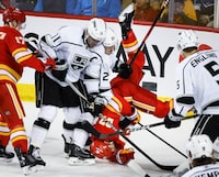 Los Angeles Kings forward Anze Kopitar (11) and defenceman Jordan Spence (21) turn Calgary Flames forward Matthew Coronato (27) upside down during second period NHL hockey action in Calgary, Saturday, March 30, 2024.THE CANADIAN PRESS/Jeff McIntosh