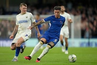 Chelsea's Enzo Fernandez is challenged by AFC Wimbledon's James Tilley during the English League Cup second round soccer match between Chelsea and AFC Wimbledon at Stamford Bridge stadium in London, Wednesday, Aug. 30, 2023. (AP Photo/Kin Cheung)