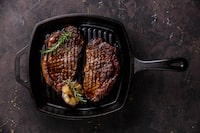 Grilled Black Angus Steak Striploin on frying cast iron Grill pan on dark background