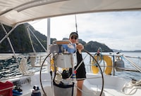 4. (most recent photo I sent you) Jessica Lee is photographed steering on Don's boat near Coron, The Philippines. She learned to follow a boat tracker during this trip with Don's help. Writer Jessica Lee sails with a stranger in the  Philippines