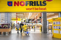Canada’s biggest grocers are investing money and space in discount stores like No Frills, Food Basics and FreshCo as shoppers look for ways to save on food. A customer pushes a shopping cart full of groceries from a NoFrills grocery store, in Toronto, on Thursday, November 23, 2023.THE CANADIAN PRESS/Chris Young