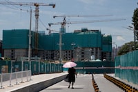 FILE PHOTO: FILE PHOTO: A woman walks near a construction site of apartment buildings in Beijing, China, July 15, 2022. REUTERS/Thomas Peter/File Photo/File Photo