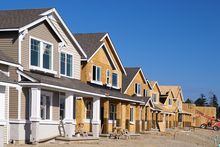 Perspective photo of a row of similar style houses during various phases of construction.