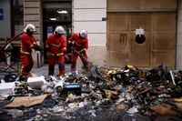 Firemen controlling the remains of a garbage fire from last night protests against the retirement bill in Paris, Friday, March 24, 2023. French President Macron's office says state visit by Britain's King Charles III is postponed amid mass strikes and protests. (AP Photo/Thomas Padilla)