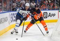 Winnipeg Jets' Mark Scheifele (55) and Edmonton Oilers' Darnell Nurse (A) (25) battle for the puck during the third period of an NHL preseason hockey game, Saturday, Oct. 2, 2021 in Edmonton, Alberta. (Jason Franson/The Canadian Press via AP)