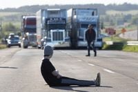 A protester blocks highway 104, in Cumberland County, N.S., Wednesday, June 23, 2021. Traffic was brought to a standstill Wednesday along the Trans-Canada Highway at Nova Scotia's boundary with New Brunswick as a protest continued over COVID-19 travel restrictions. THE CANADIAN PRESS/Riley Smith