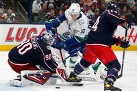 Columbus Blue Jackets' Elvis Merzlikins, left, makes a save as teammate Gustav Nyquist, right, and Vancouver Canucks' Vasily Podkolzin looks for the rebound during the third period of an NHL hockey game Friday, Nov. 26, 2021, in Columbus, Ohio. (AP Photo/Jay LaPrete)
