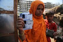 In this March 9, 2021 file photo, Rahima Kato, a Rohingya woman displays identity cards of her family members issued by United Nations High Commissioner for Refugees (UNHCR) at their makeshift camp on the outskirts of Jammu, India. Four Indian states bordering Myanmar have stepped up measures to prevent refugees from entering India through a porous border following last month's military coup in the Southeast Asian country, a government official said Saturday. (AP Photo/Channi Anand)