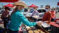 Calgary Stampede volunteer Jessica Rooney, left, cooks pancakes during a drive-thru pancake breakfast as people try to enjoy the Calgary Stampede even though it has been cancelled in Calgary, Saturday, July 4, 2020. THE CANADIAN PRESS/Jeff McIntosh