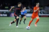 Oct 6, 2021; Portland, Oregon, USA; Portland Thorns forward Christine Sinclair (12) dribbles the ball away from Houston Dash midfielder Sophie Schmidt (13) during the second half of a NWSL soccer match at Providence Park. Mandatory Credit: Soobum Im-USA TODAY Sports