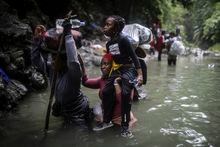 Haitian migrants wade through water as they cross the Darien Gap from Colombia to Panama in hopes of reaching the U.S., Tuesday, May 9, 2023. Pandemic-related U.S. asylum restrictions, known as Title 42, are to expire Thursday, May 11. (AP Photo/Ivan Valencia)