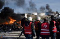 Unionists of the French union General Confederation of Labour (CGT) block the access to oil terminals at the Total Energies refinery with makeshift roadblocks and fires to protest against the government's proposed pensions overhaul in Donges, western France on March 16, 2023. - A proposed reform of pension system, which has sparked massive protests and strikes since the start of the year, is to be put to a vote in parliament in a decisive moment for French President. The Senate and lower house National Assembly are set to hold ballots on the legislation to raise the retirement age to 64. (Photo by LOIC VENANCE / AFP) (Photo by LOIC VENANCE/AFP via Getty Images)