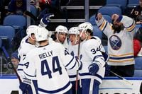 A Buffalo Sabres fan shows two thumbs-down as Toronto Maple Leafs players celebrate a goal by right wing Ondrej Kase (25) during the second period of an NHL hockey game against the Buffalo Sabres on Saturday, Nov. 13, 2021, in Buffalo, N.Y. (AP Photo/Joshua Bessex)