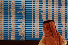 A trader watches an electronic share price display at the Doha Stock Exchange in Doha May 28, 2015.