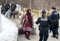 RCMP officers stop people as they enter Canada via Roxham road on the Canada/US border in Hemmingford, Que., Saturday, March 25, 2023. THE CANADIAN PRESS/Graham Hughes