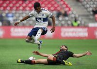 Vancouver Whitecaps' Pedro Vite, top left, leaps to avoid a sliding tackle by Valour FC's Tony Mikhael during the second half of a preliminary round Canadian Championship soccer match, in Vancouver, on Wednesday, May 11, 2022. THE CANADIAN PRESS/Darryl Dyck