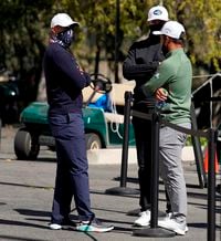 From left, Tiger Woods, Dustin Johnson and Xander Schauffele talk after high winds suspended play during the third round of the Genesis Invitational golf tournament at Riviera Country Club, Saturday, Feb. 20, 2021, in the Pacific Palisades area of Los Angeles. (AP Photo/Ryan Kang)