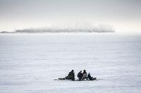 Ice fishermen huddle over a hole in the ice on Ghost Lake Reservoir near Cochrane, Alta., Sunday, Dec. 27, 2020. Alberta's United Conservative government has moved on a plan to split the job of wildlife management in the province, creating a new department of hunting and fishing in the Forestry, Parks and Tourism Ministry. THE CANADIAN PRESS/Jeff McIntosh